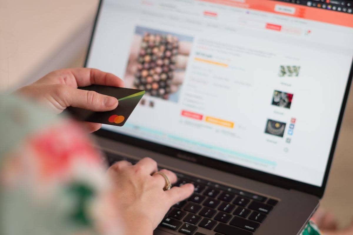 ilustrasi seseorang yang berbelanja online menggunakan kartu kredit dengan laptop 