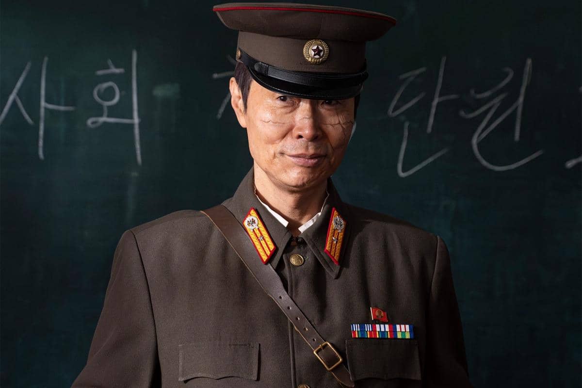 Seorang aktor mengenakan seragam militer lengkap dengan topi dan lencana dalam adegan drama Agent Kim Reactivated.