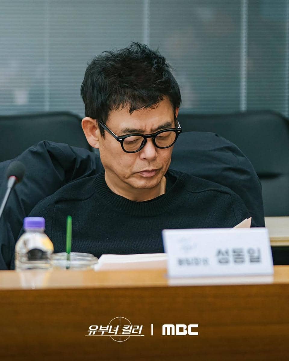 Seorang pria berkacamata membaca naskah di meja rapat saat sesi pembacaan naskah drama Killer of Married Woman produksi MBC.
