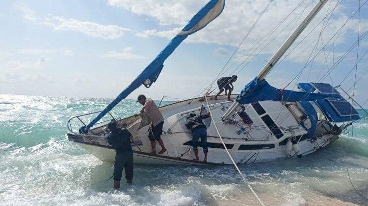 Beberapa orang berusaha mengevakuasi kapal pesiar berbendera Australia yang terdampar di tepi Pantai Duile, Rote Ndao.