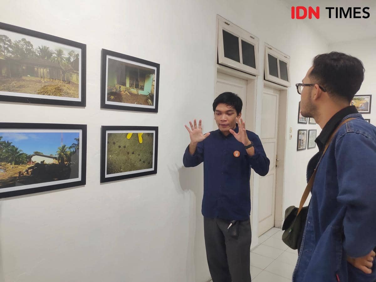 Dua orang berdiskusi di depan deretan foto bertema penyelamatan satwa terdampak banjir Sumatra dalam pameran Centre for Orangutan Protection.