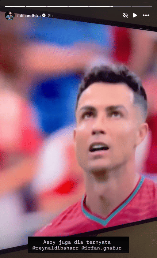 Seorang pemain sepak bola mengenakan jersey merah tampak di lapangan dengan ekspresi fokus saat pertandingan berlangsung.