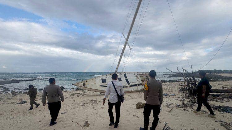 Beberapa petugas berdiri di tepi Pantai Duile, Rote Ndao, memeriksa kapal pesiar berbendera Australia bernama Balamara yang terdampar di pasir.