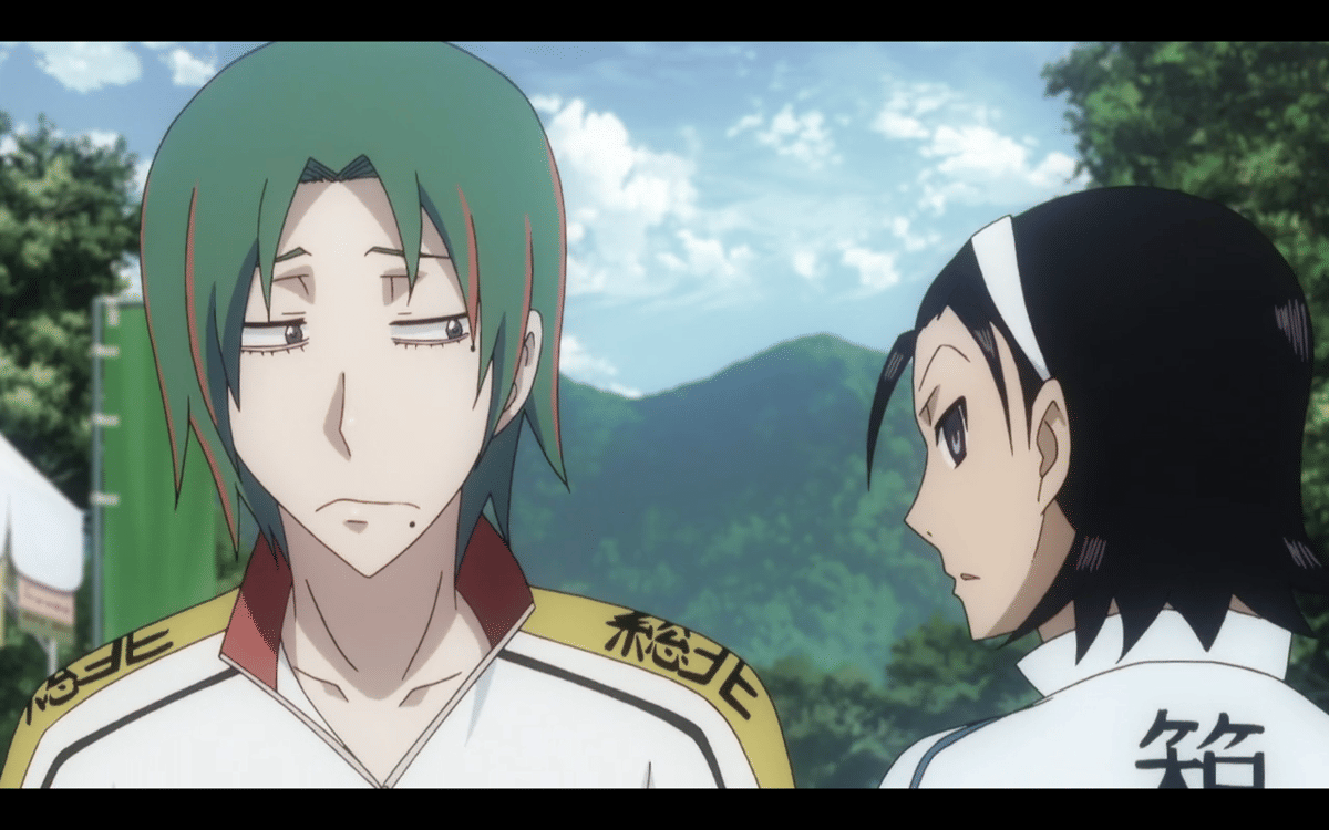Dua karakter anime Yowamushi Pedal berbicara di luar ruangan dengan latar pegunungan dan langit cerah di belakang mereka.