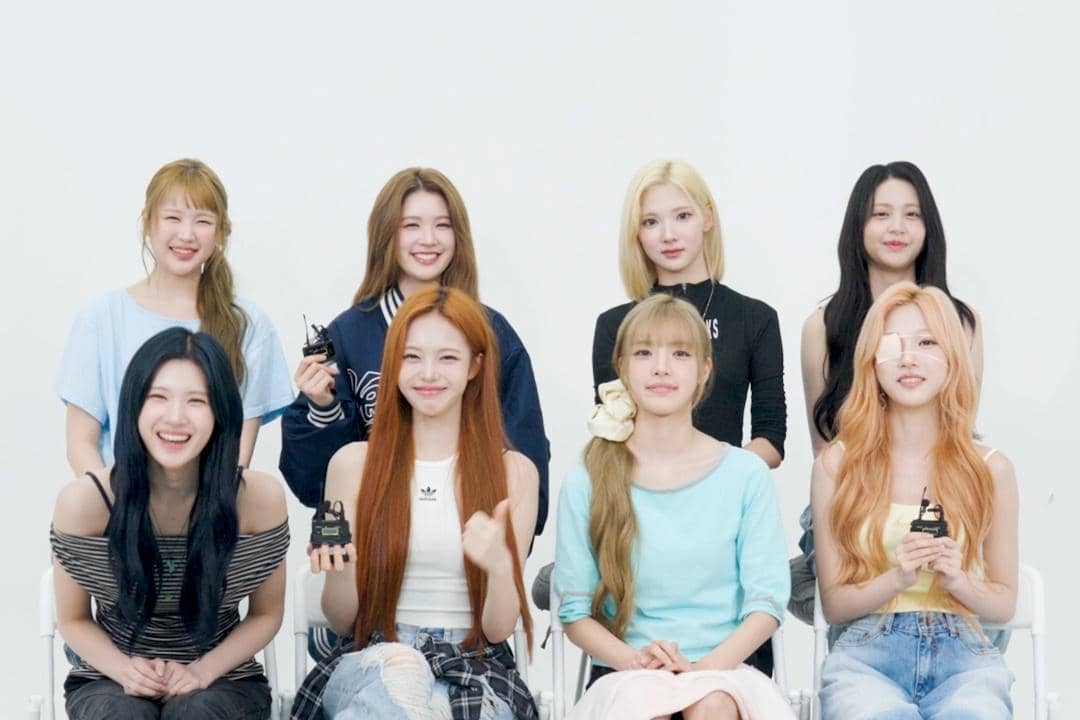 Delapan anggota Hearts2Hearts duduk bersama sambil tersenyum dalam wawancara untuk comeback Lemon Tang dengan latar putih sederhana.