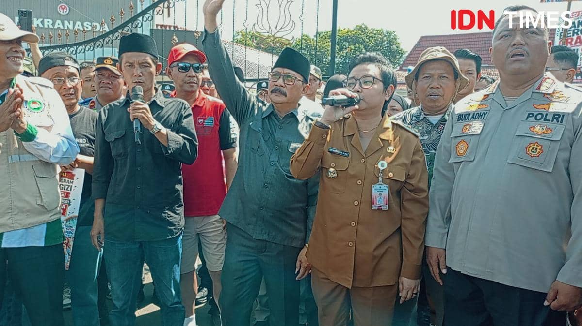 Plt Bupati Cilacap berbicara menggunakan mikrofon di tengah kerumunan saat menemui pendemo aksi damai bersama aparat dan masyarakat.