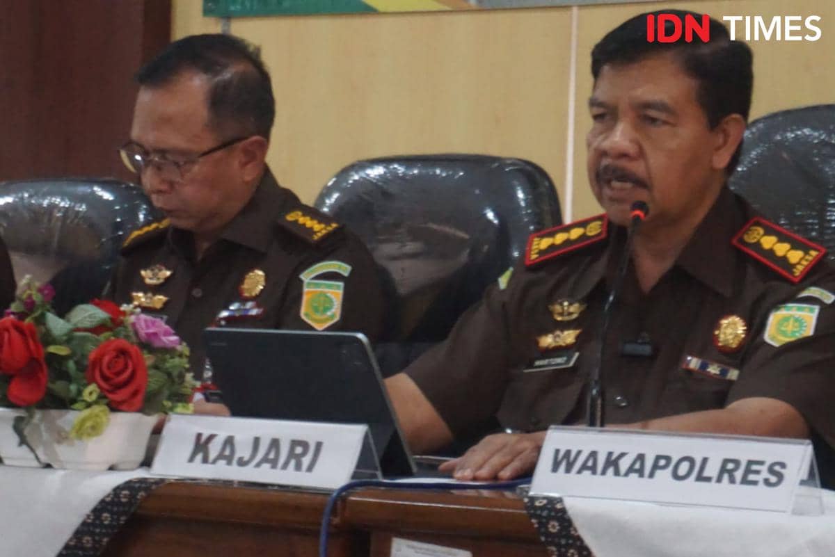 Dua pejabat Kejaksaan Negeri Yogyakarta mengenakan seragam dinas cokelat sedang duduk di meja rapat dengan papan nama dan mikrofon di depan mereka.