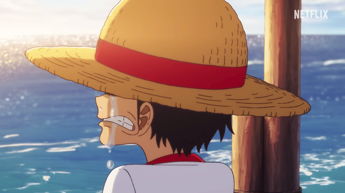 Karakter anime mengenakan topi jerami menangis di tepi laut dengan latar matahari terbenam yang memantul di permukaan air.