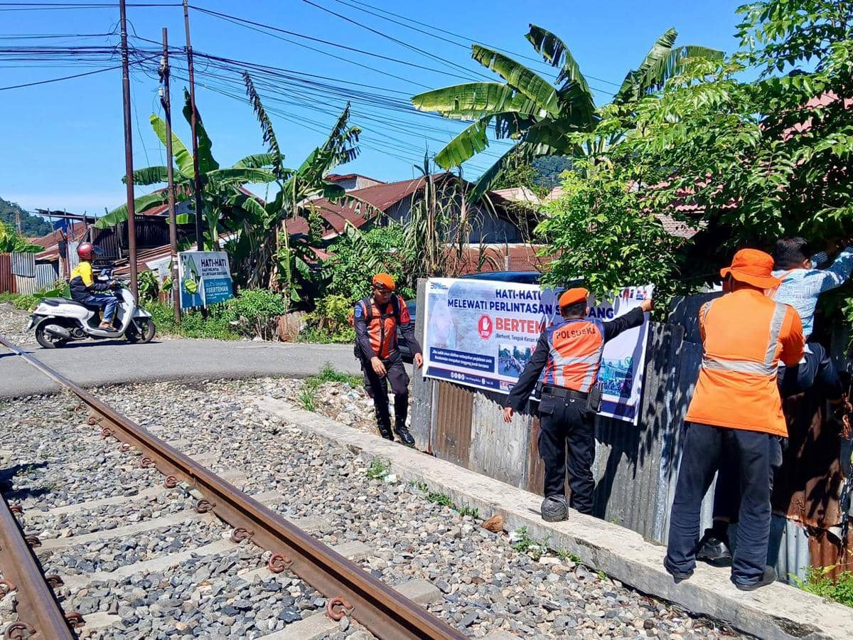 Petugas KAI memasang spanduk imbauan di perlintasan sebidang (Dok. KAI)