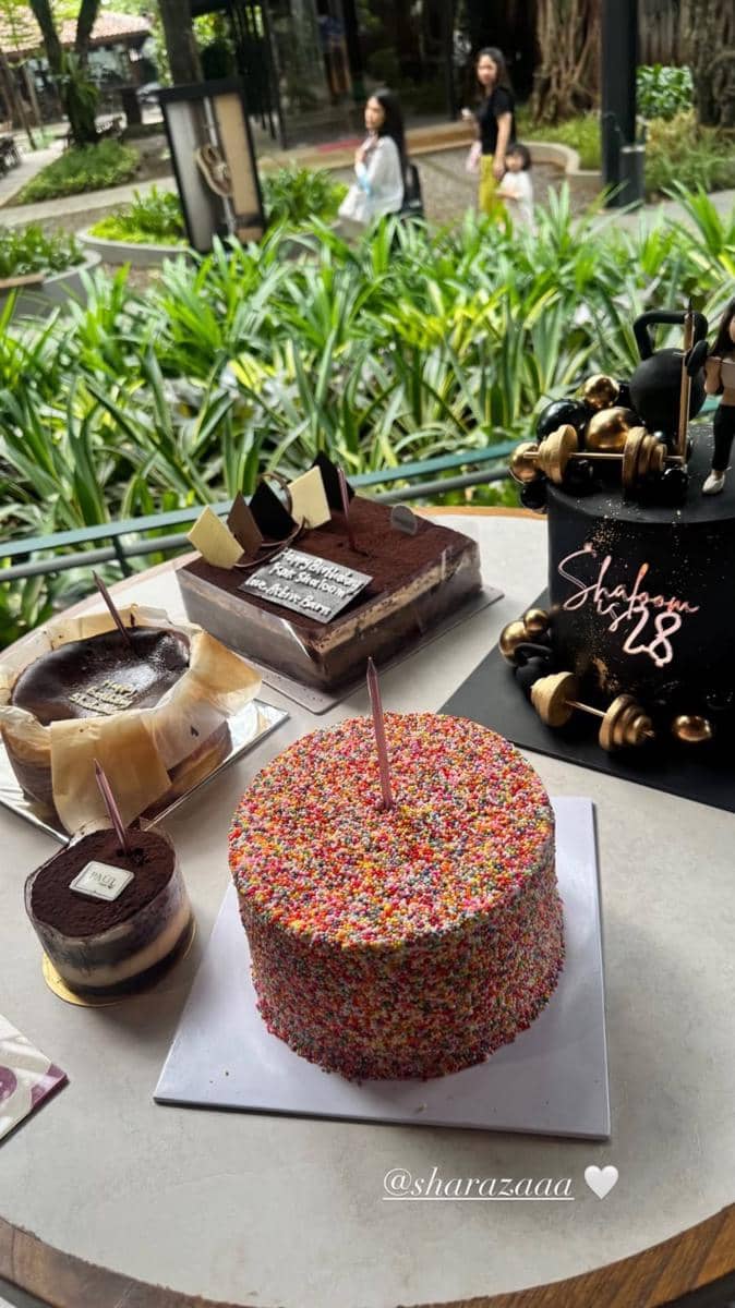 Beberapa kue ulang tahun dengan dekorasi warna-warni dan lilin di atas meja, salah satunya bertuliskan usia 28 tahun.
