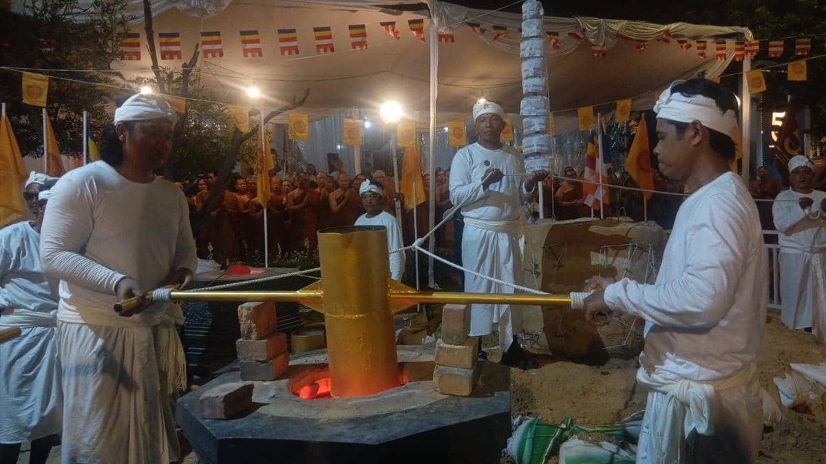 Para peserta berpakaian putih melakukan prosesi pengecoran Ruppang Buddha Nusantara di Jakarta dengan latar biksu dan bendera Buddhis.