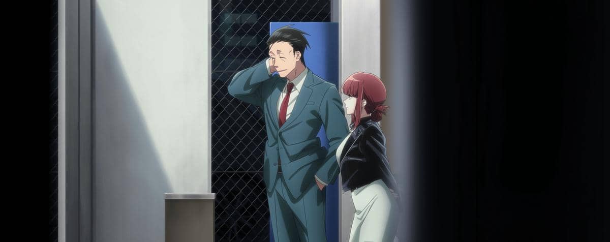 Dua karakter anime berdiri di area belakang gedung, satu pria mengenakan setelan jas dan satu wanita berambut merah berbicara santai.