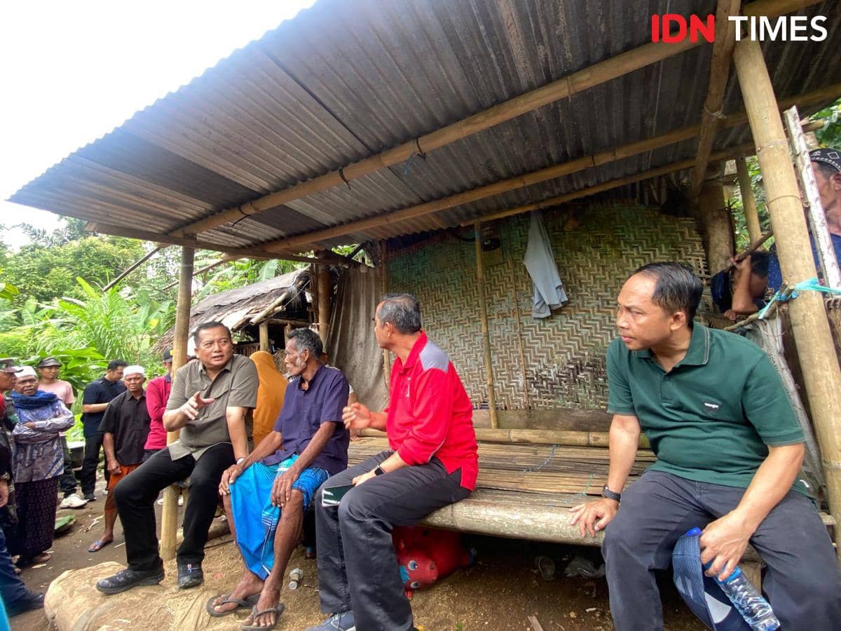 Beberapa orang duduk dan berbincang di depan gubuk bambu beratap seng di Desa Mekarsari yang tampak sederhana dan dikelilingi warga.