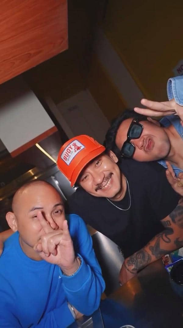 Tiga pria berpose santai dan tersenyum di pesta perpisahan Indonesian Idol Season 14, salah satunya mengenakan topi oranye.