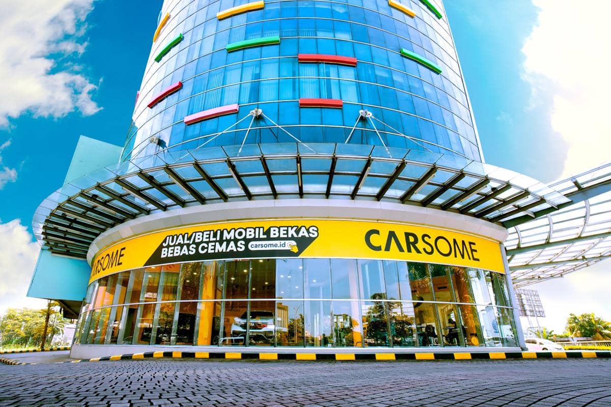 Tampak depan diler Carsome di BSD Junction dengan bangunan kaca tinggi dan papan nama kuning bertuliskan Carsome.
