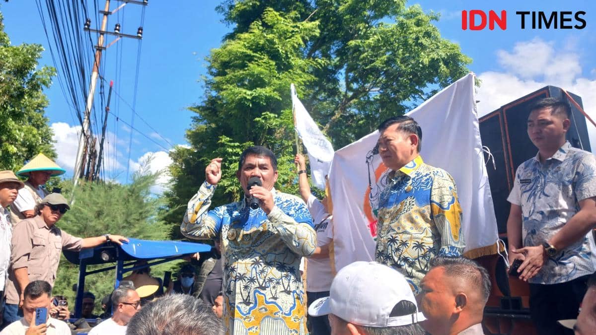 Dua pejabat Sulawesi Utara berbicara di depan massa aksi damai di Manado dengan latar pepohonan dan langit cerah.