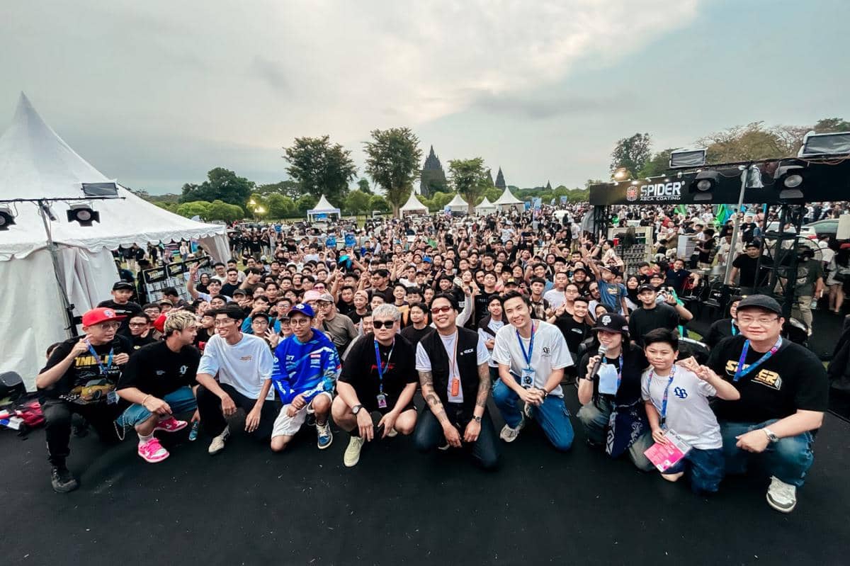 Kerumunan peserta dan panitia berfoto bersama di acara Road to IMX yang digelar di area luar ruangan dengan latar tenda putih dan pepohonan.