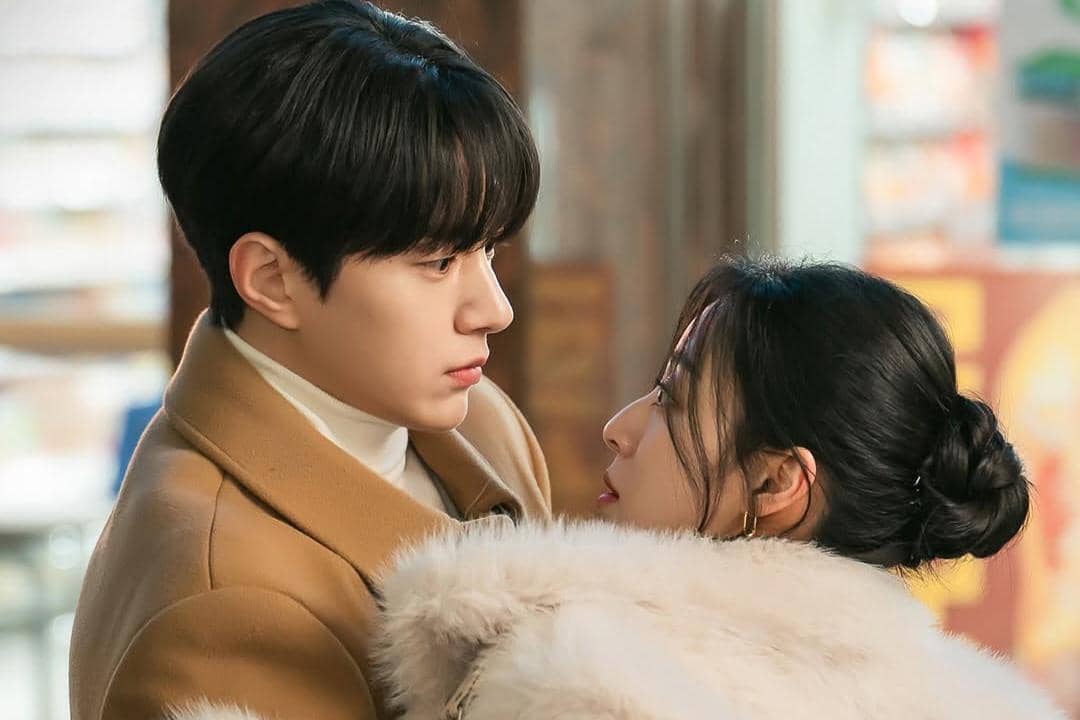 Dua pemeran utama drama Love In Sync saling menatap dekat dengan ekspresi emosional di suasana musim dingin.