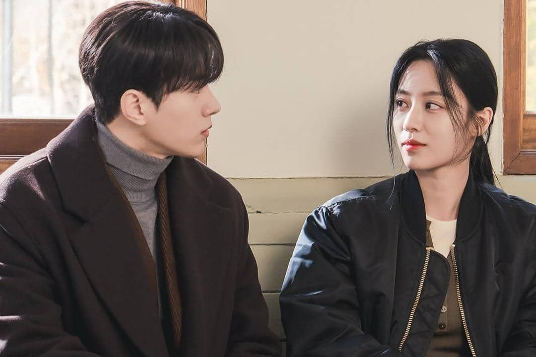 Dua pemeran drama Love In Sync duduk berhadapan di dekat jendela, saling menatap dengan ekspresi serius dan hangat.