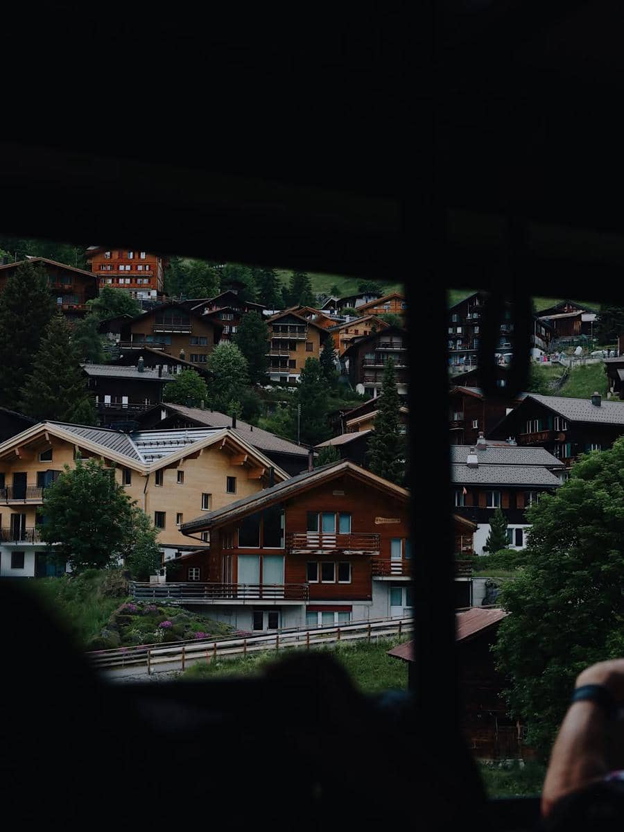 Pemandangan deretan rumah kayu tradisional di Desa Lauterbrunnen yang dikelilingi pepohonan hijau dan perbukitan.