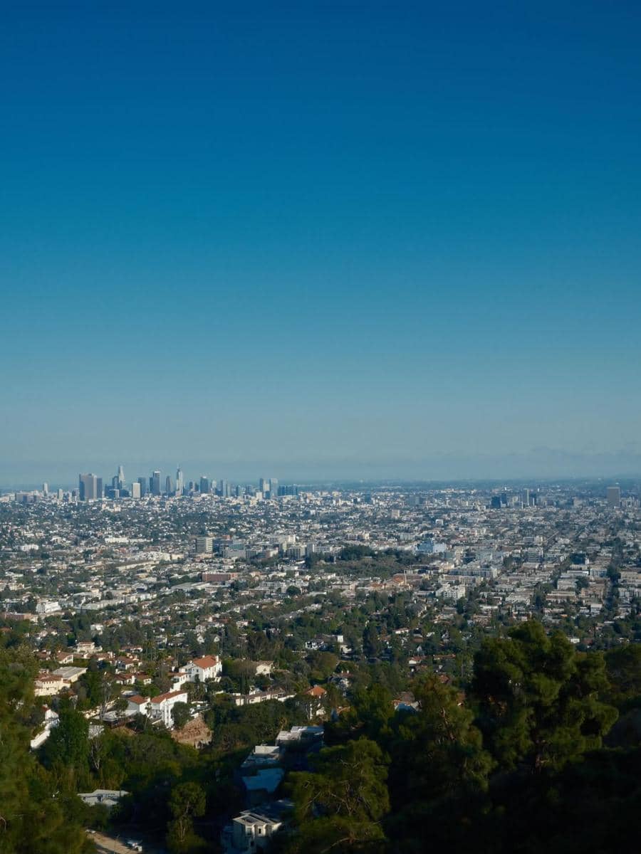 Pemandangan udara kota Hollywood dengan gedung pencakar langit di kejauhan di bawah langit biru cerah pada siang hari.