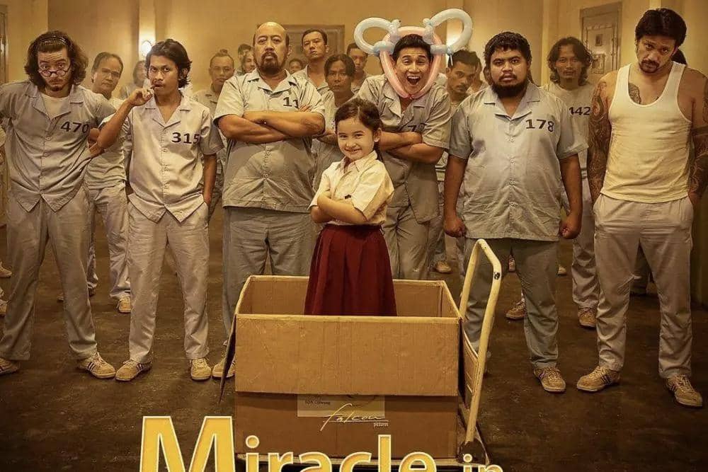 Poster film Miracle in Cell No. 7 menampilkan seorang anak perempuan berdiri di dalam kotak dengan latar para narapidana mengenakan seragam abu-abu.
