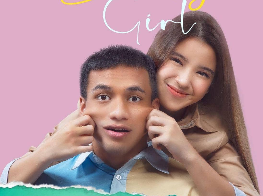 Dua pemeran utama film My Sassy Girl berpose dengan ekspresi lucu, perempuan menarik pipi pria di latar berwarna merah muda.