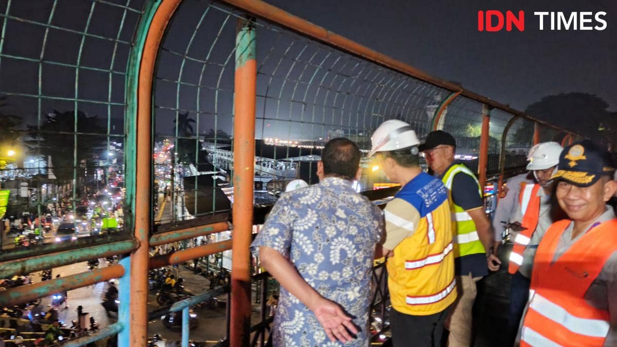 Sejumlah petugas dan pejabat mengenakan rompi keselamatan serta helm proyek meninjau pembongkaran JPO Paledang di Bogor pada malam hari.