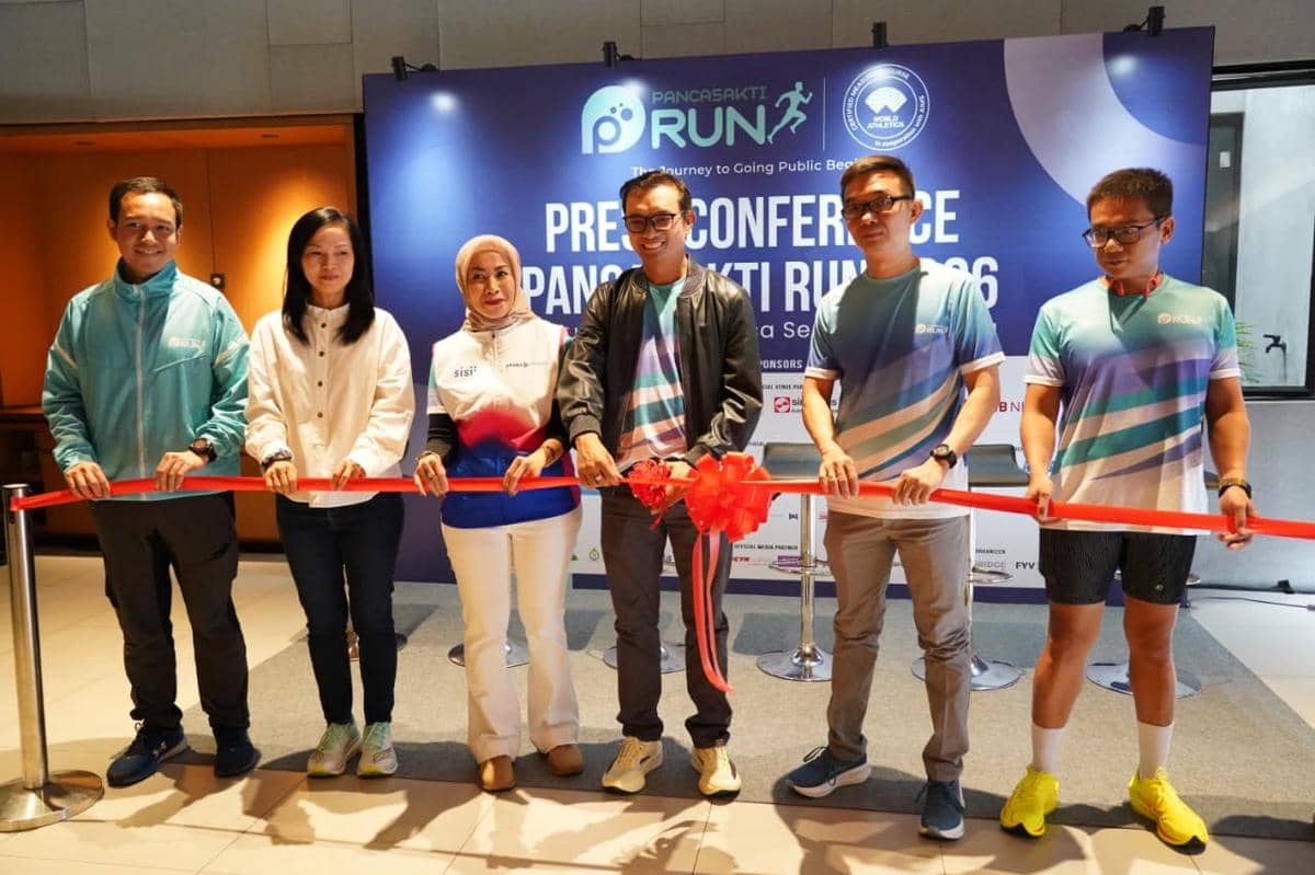 Enam orang berdiri bersama memegang pita merah dalam acara konferensi pers Pancasakti Run 2026 dengan latar belakang spanduk acara.