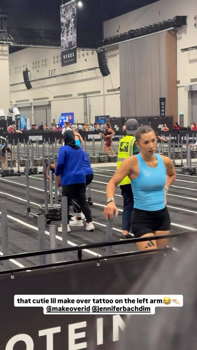 Peserta wanita mengenakan tank top biru dan celana pendek hitam berpartisipasi dalam ajang kebugaran HYROX Jakarta 2026 di area indoor.