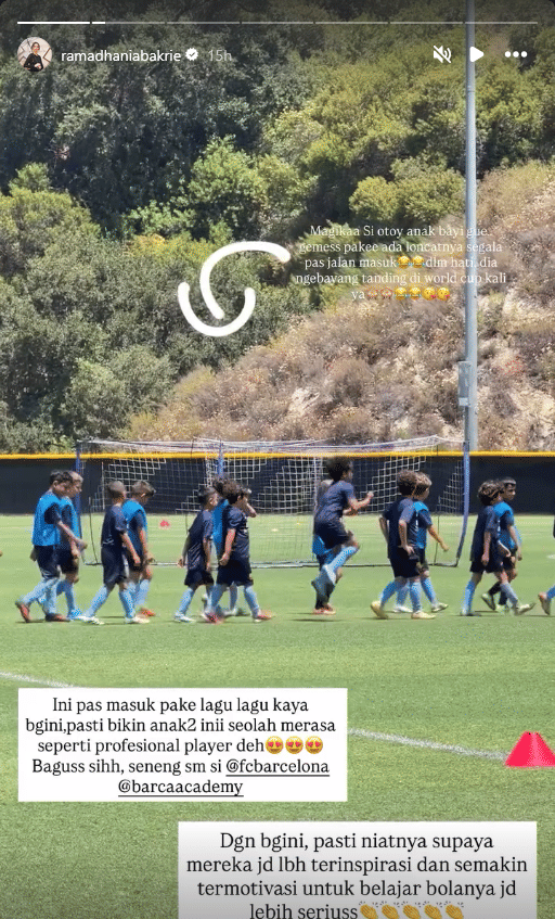 Sekelompok anak-anak berlatih sepak bola di lapangan hijau dengan pelatih di Barcelona Academy, mengenakan seragam biru tua dan biru muda.