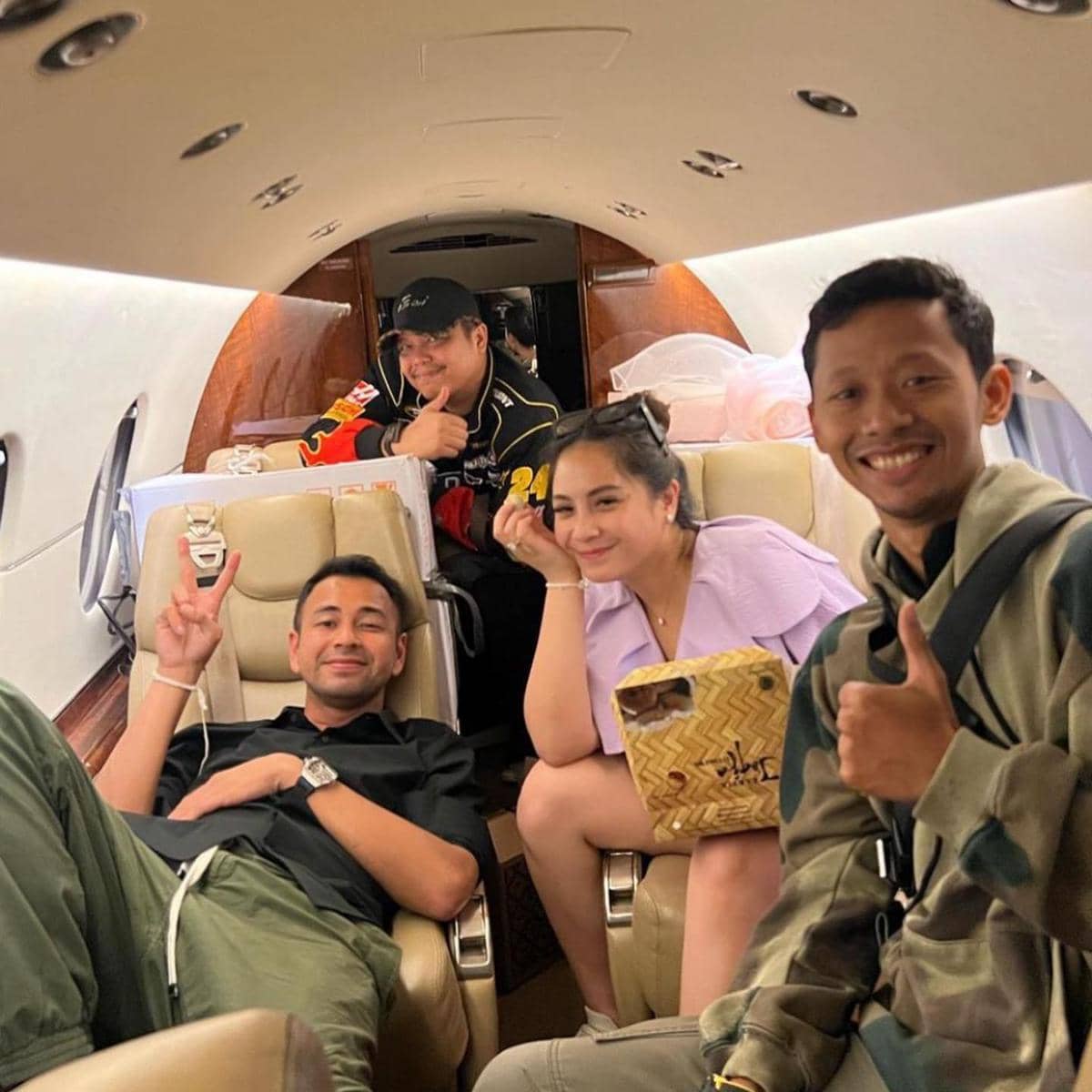 Empat orang duduk santai di dalam kabin jet pribadi, tersenyum dan berpose dengan suasana akrab selama penerbangan.
