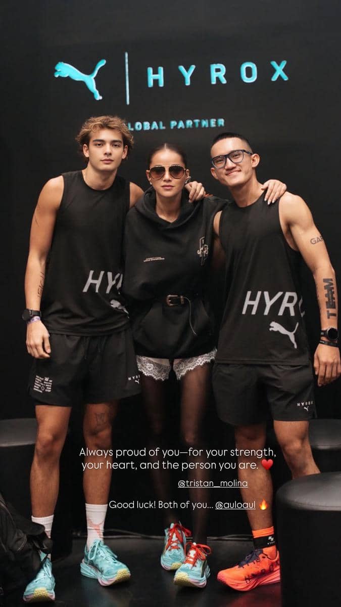 Tiga orang mengenakan pakaian olahraga hitam bertuliskan HYROX berpose di depan latar bertema HYROX dengan logo Puma di acara HYROX Jakarta 2026.