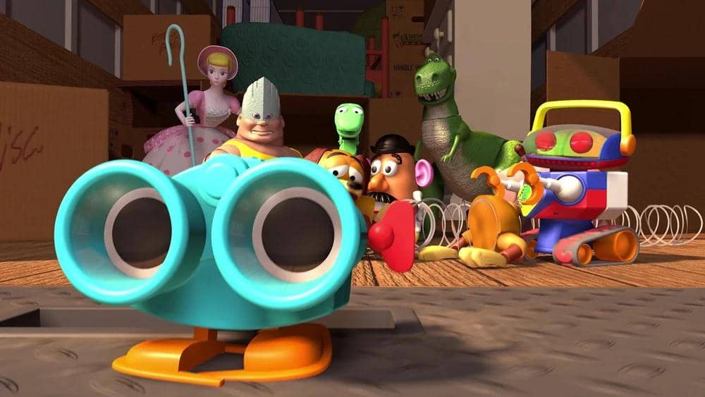 Beberapa karakter mainan dari film animasi Toy Story berkumpul di sebuah ruangan dengan latar penuh kotak kardus.