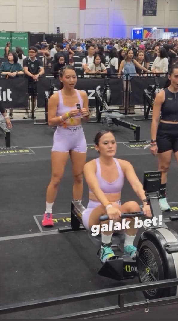 Peserta wanita mengenakan pakaian olahraga ungu sedang menggunakan mesin dayung di ajang HYROX Jakarta 2026 dengan banyak penonton di belakangnya.