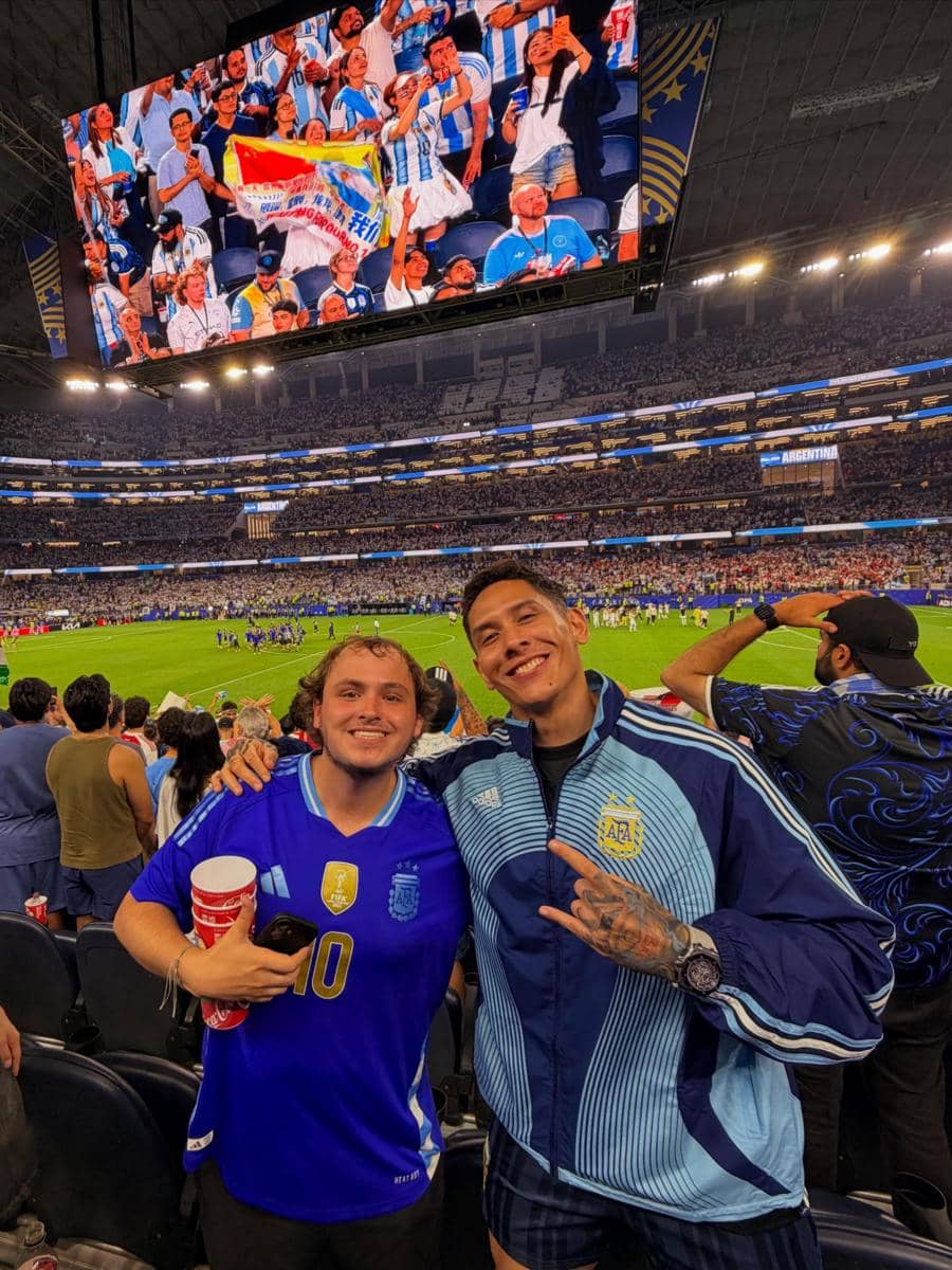 Dua penonton mengenakan jersey Argentina berpose di stadion penuh penonton saat pertandingan Piala Dunia 2026 berlangsung.