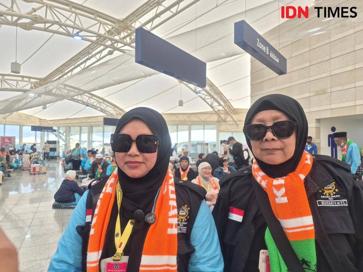 Dua perempuan berhijab mengenakan kacamata hitam dan syal oranye di Bandara Internasional Prince Mohammed bin Abdulaziz, Madinah.