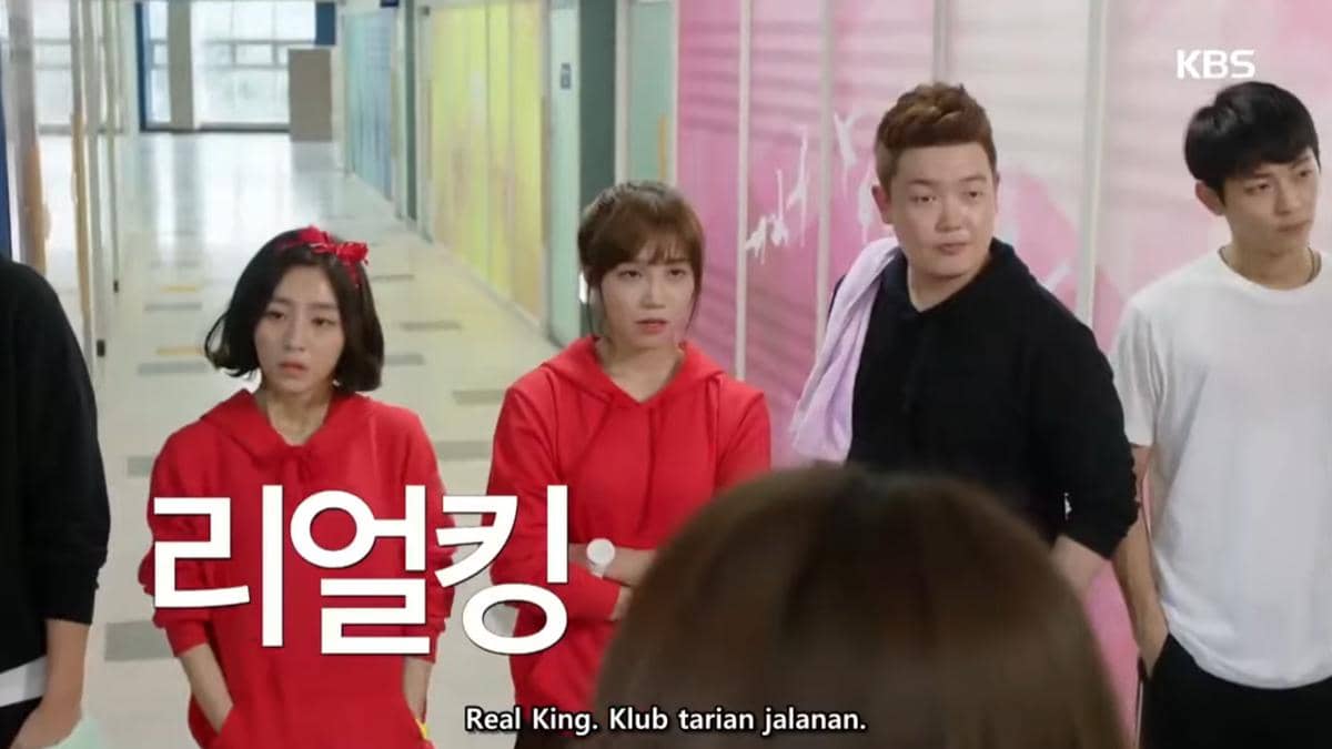 Beberapa karakter mengenakan pakaian kasual berdiri di koridor sekolah dalam cuplikan drama Korea Cheer Up.