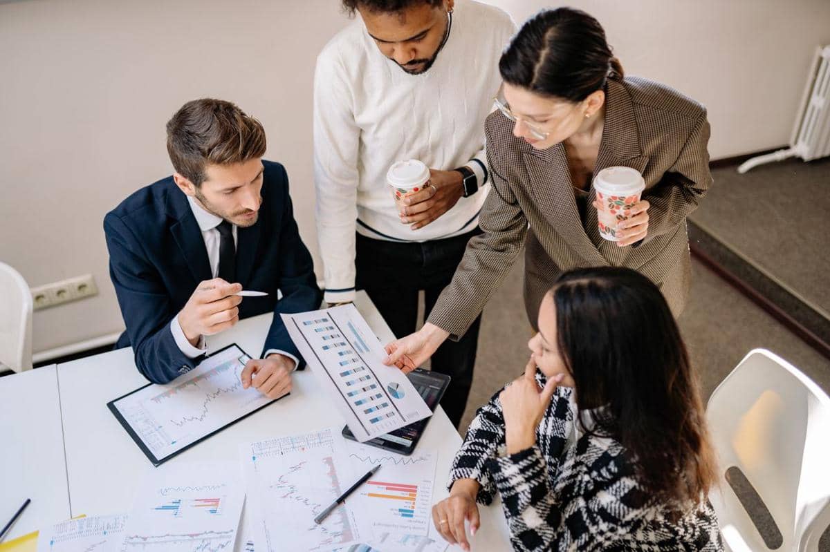 ilustrasi empat rekan kerja mendiskusikan data dan strategi dalam lingkungan kantor