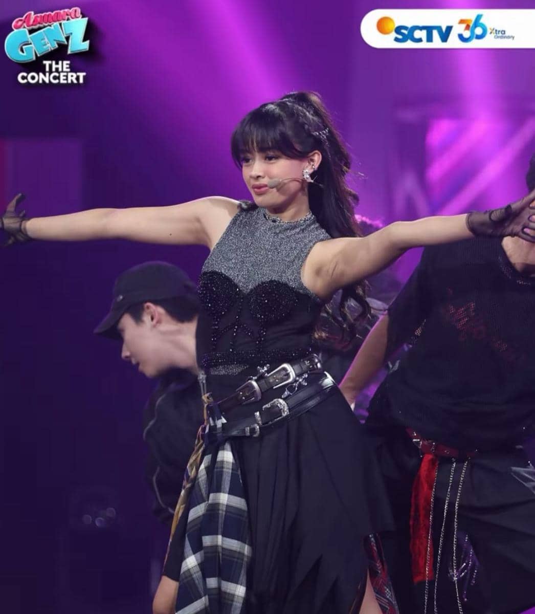 Seorang penyanyi muda tampil energik di panggung Asmara Gen Z The Concert dengan pencahayaan ungu dan penari latar di belakangnya.