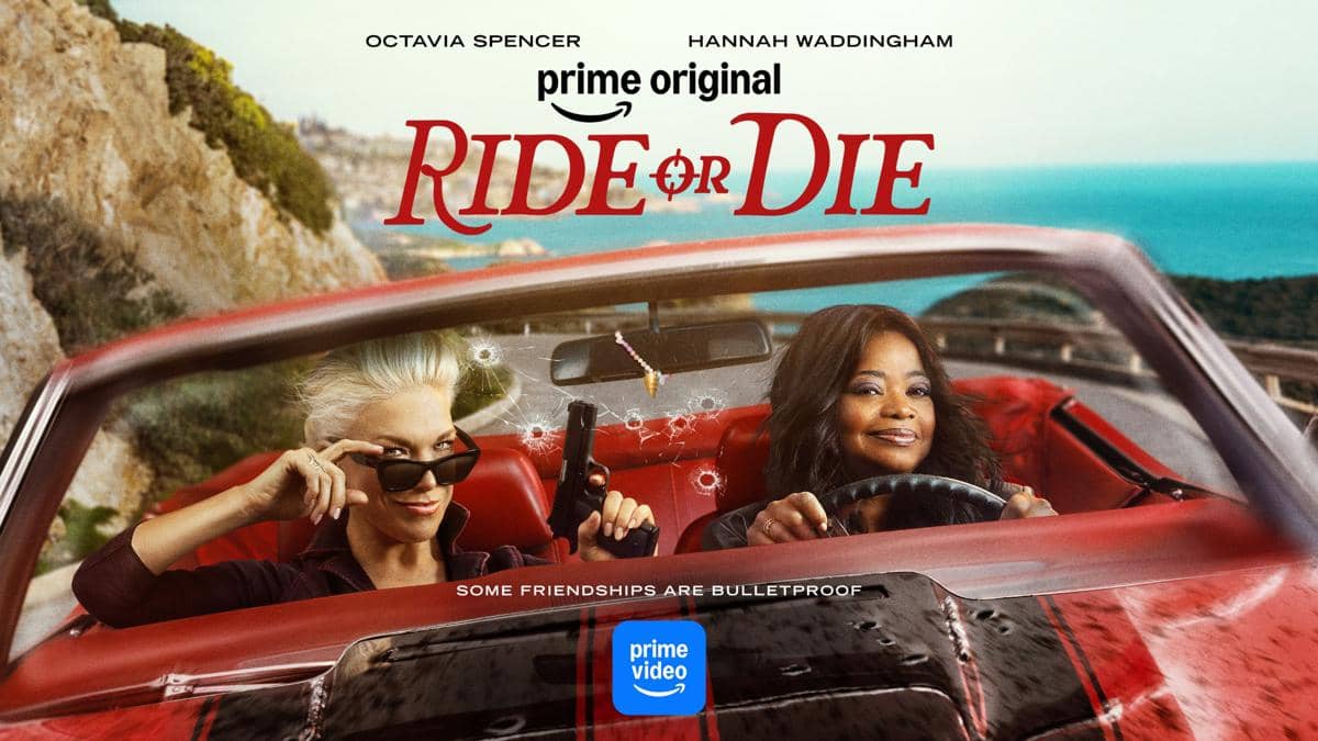 Dua wanita duduk di mobil convertible merah di tepi pantai dengan lubang peluru di kaca depan, promosi serial Ride or Die di Prime Video.