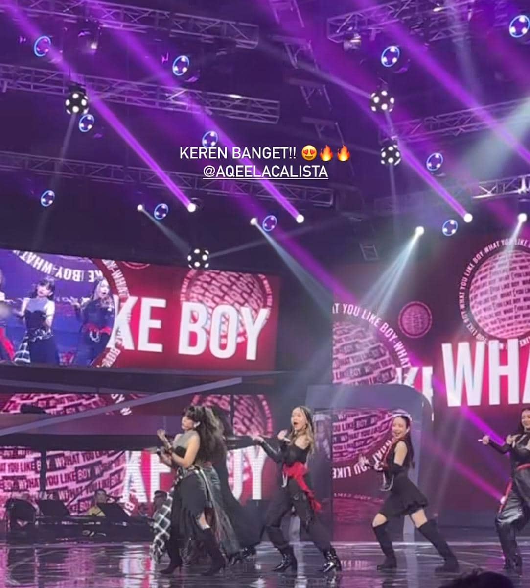 Penampilan panggung energik sekelompok penari wanita dengan pencahayaan ungu dan latar layar besar bertuliskan 'LIKE BOY' di konser Asmara Gen Z.