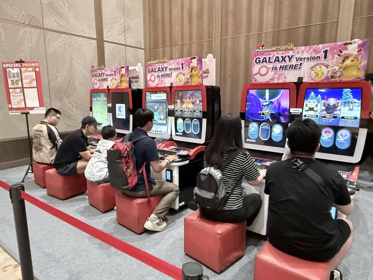 Beberapa orang bermain di mesin arcade bertema Pokémon di acara Indonesia Master Ball League di dalam ruangan.