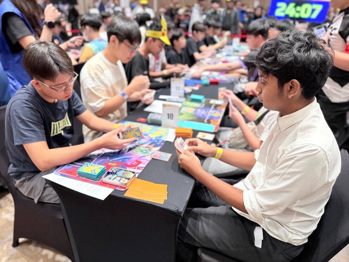 Para peserta duduk berhadapan di meja turnamen Indonesia Master Ball League, fokus memainkan kartu permainan dengan suasana kompetitif.