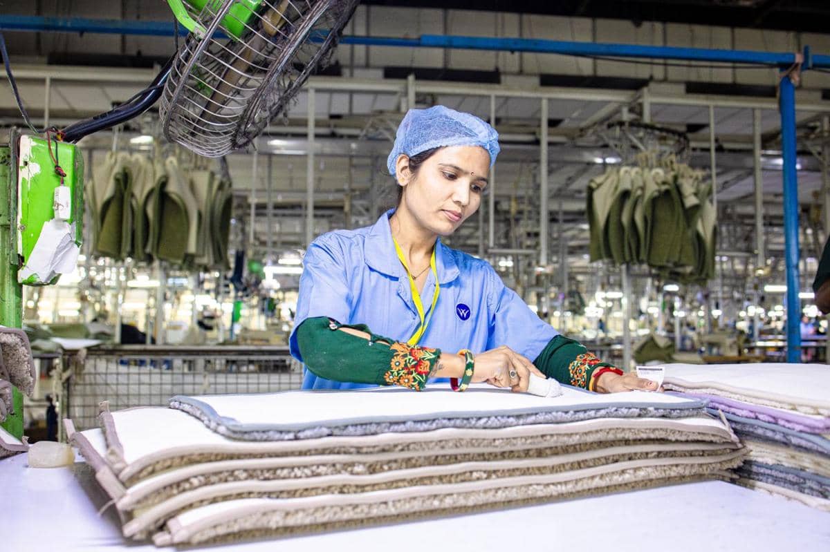 ilustrasi seorang pekerja tekstil wanita di pabrik sedang memeriksa lapisan kain