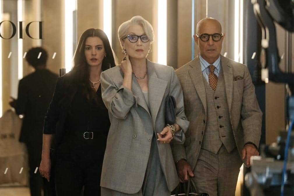 Tiga karakter berpakaian formal berjalan di koridor modern dalam cuplikan film The Devil Wears Prada 2 produksi 20th Century Studio.