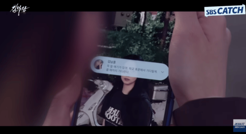 Seseorang memegang ponsel yang menampilkan pesan dan foto wanita berpakaian hitam di adegan drama Agent Kim Reactivated.