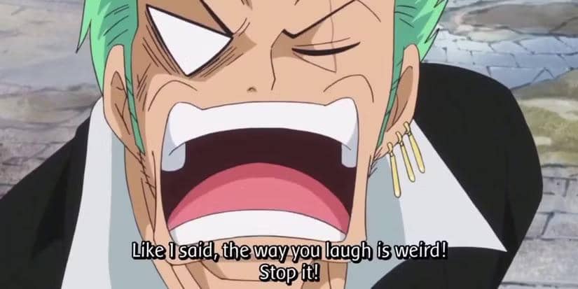 Zoro dari anime One Piece tertawa lebar dengan ekspresi mengejek saat menanggapi suara Pica di latar jalan berbatu.