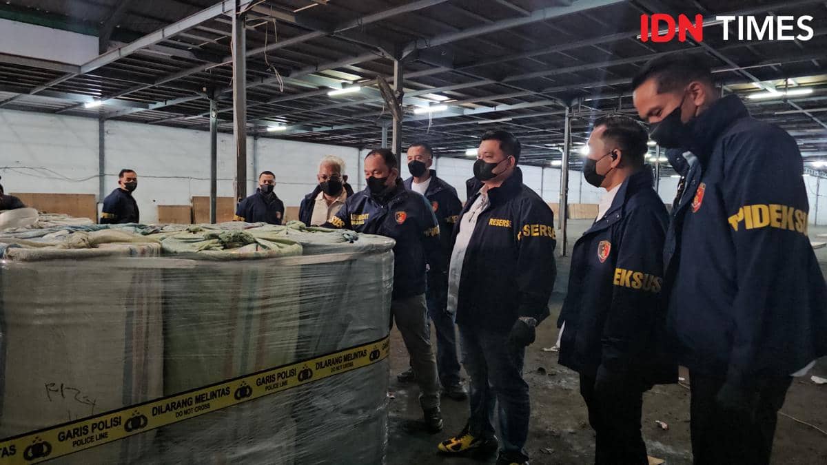 Petugas Ditipideksus Bareskrim Polri memeriksa tumpukan drum berisi sianida yang disita di sebuah gudang di Jakarta, dibatasi garis polisi.
