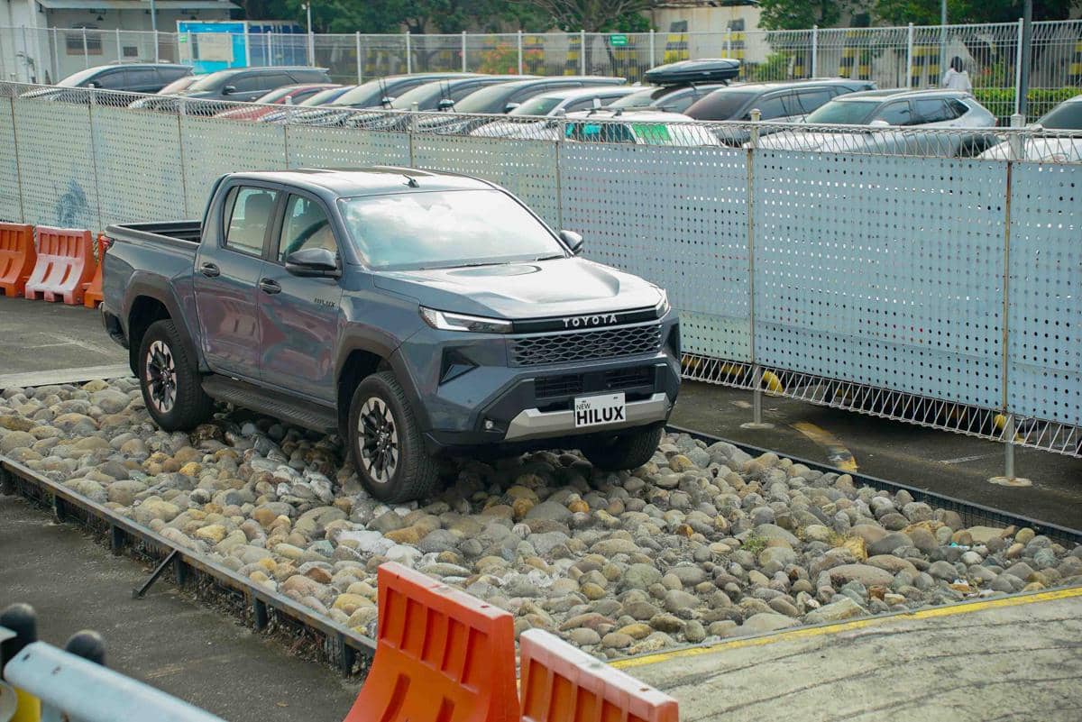 Toyota Hilux baru berwarna abu-abu melintasi jalur berbatu untuk menunjukkan peningkatan ground clearance hingga 312 mm.